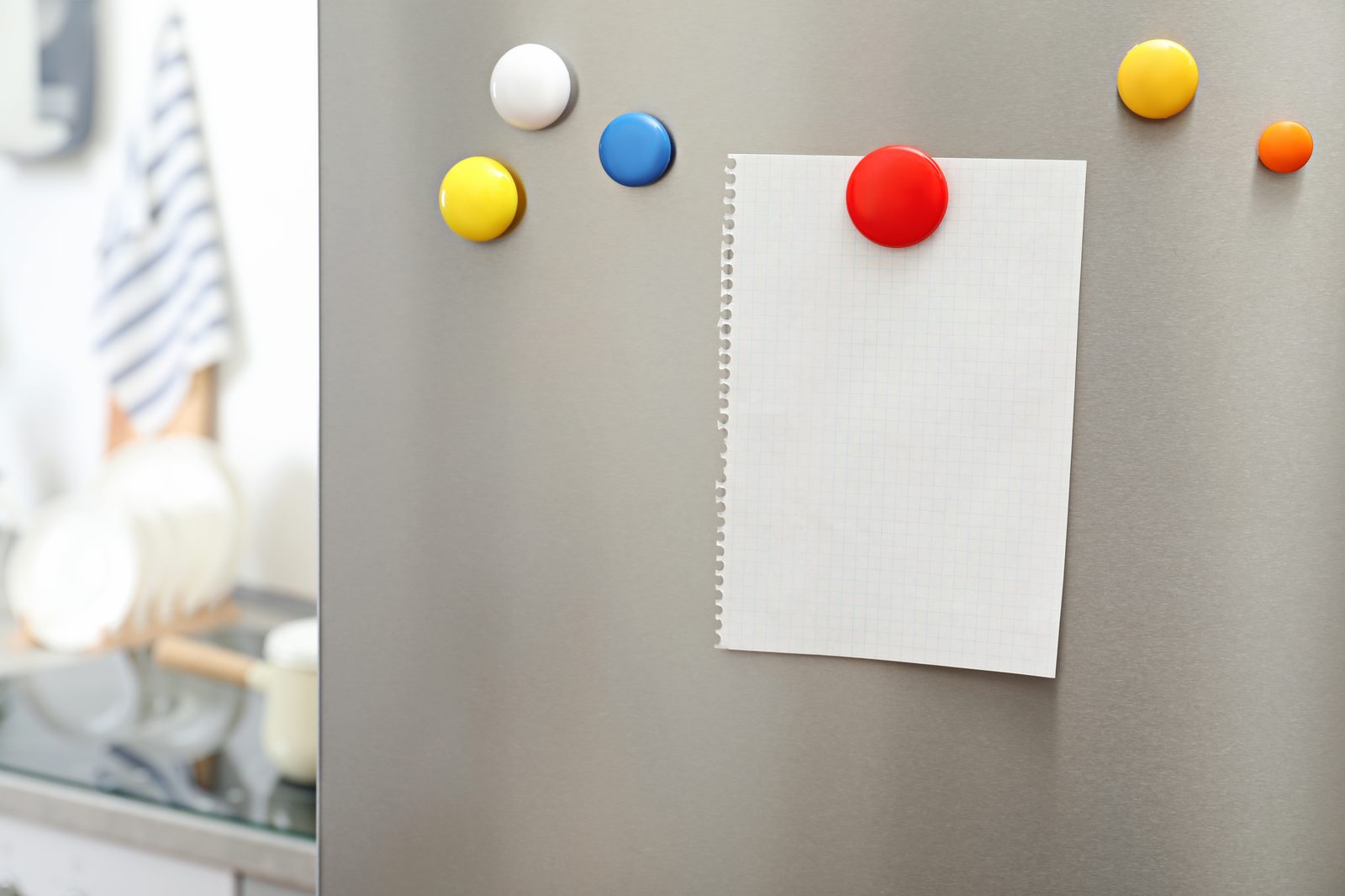 Notepad held by magnets on a fridge door during hosting prep