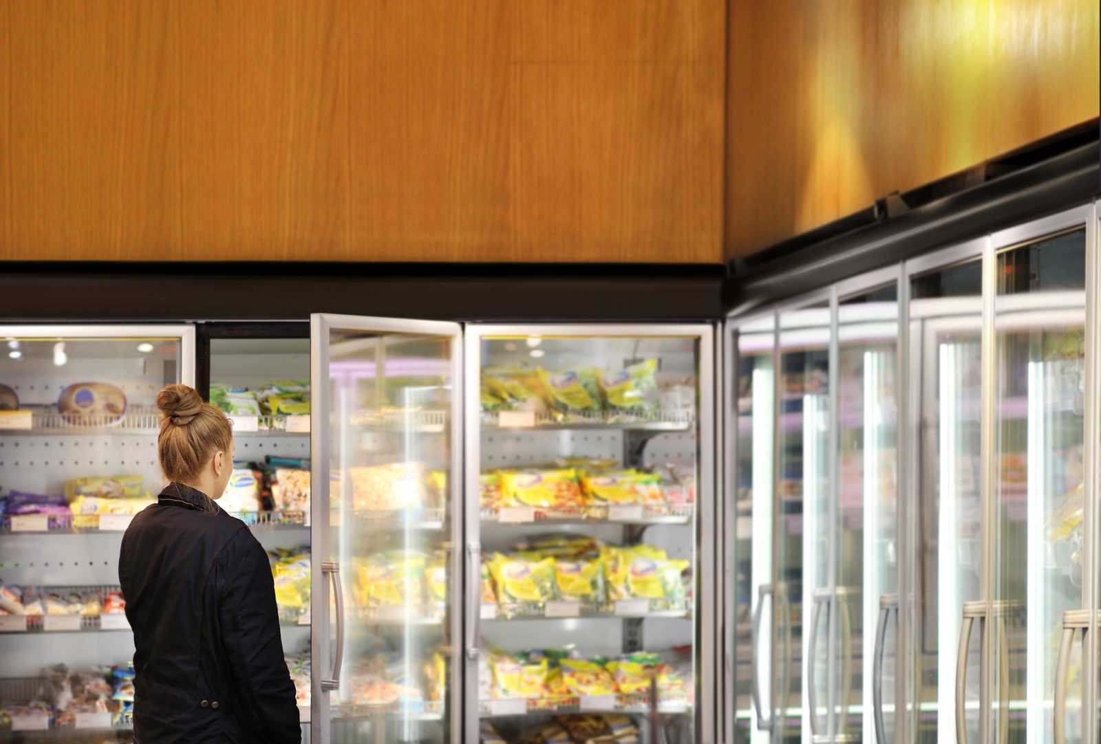 Woman lifting frozen packs out of a top-opening freezer